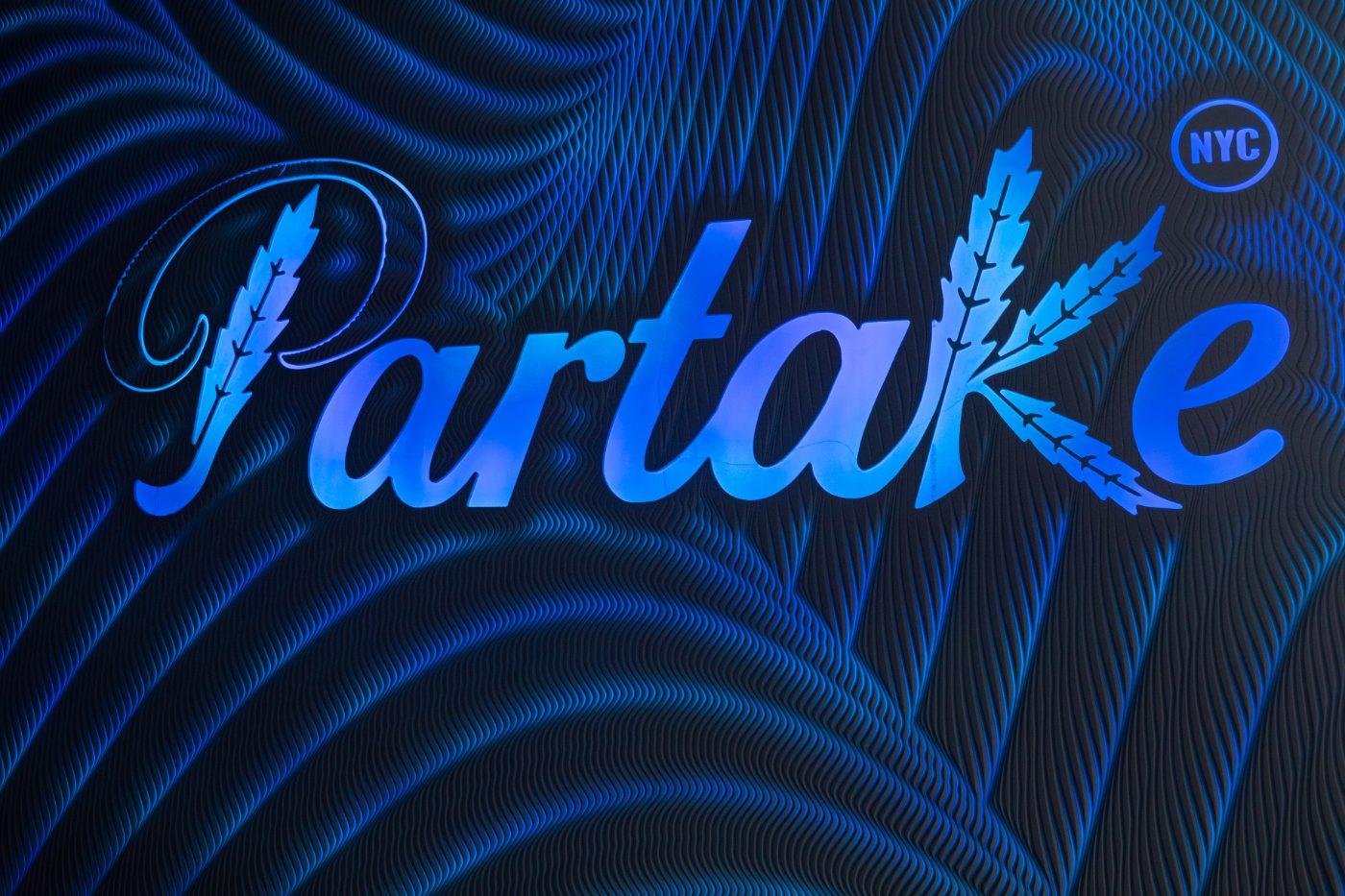 The Partake logo wall lit in blue