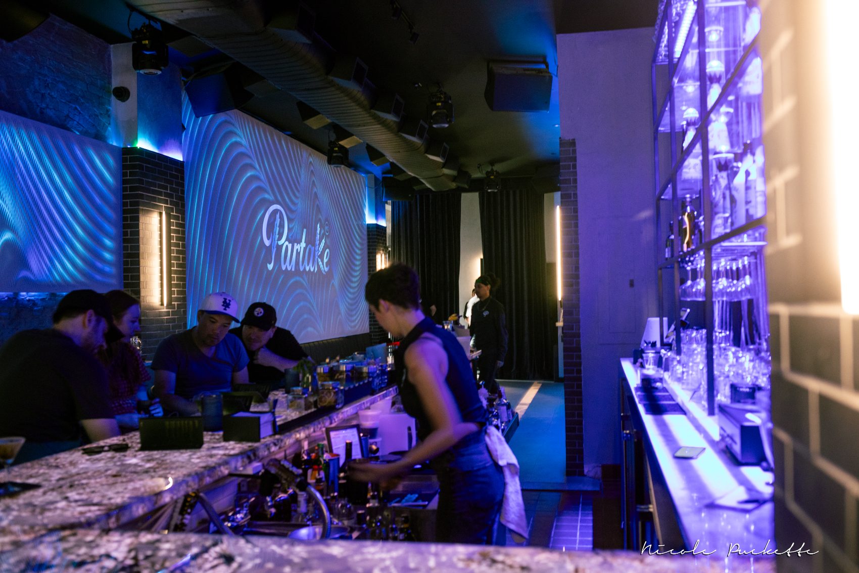 The main bar at Partake NYC lit blue with the Partake wall behind it, set for a full buyout