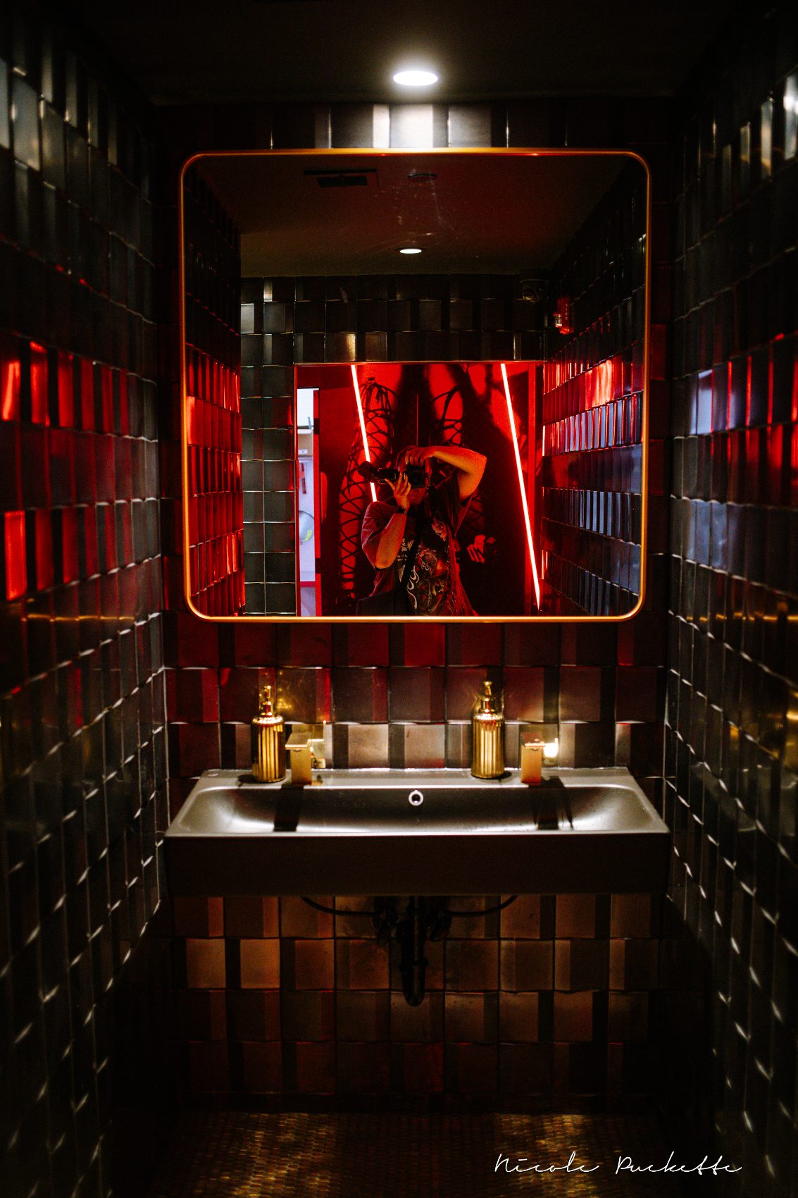 Tiled powder room with a gold-framed mirror off the Red Room